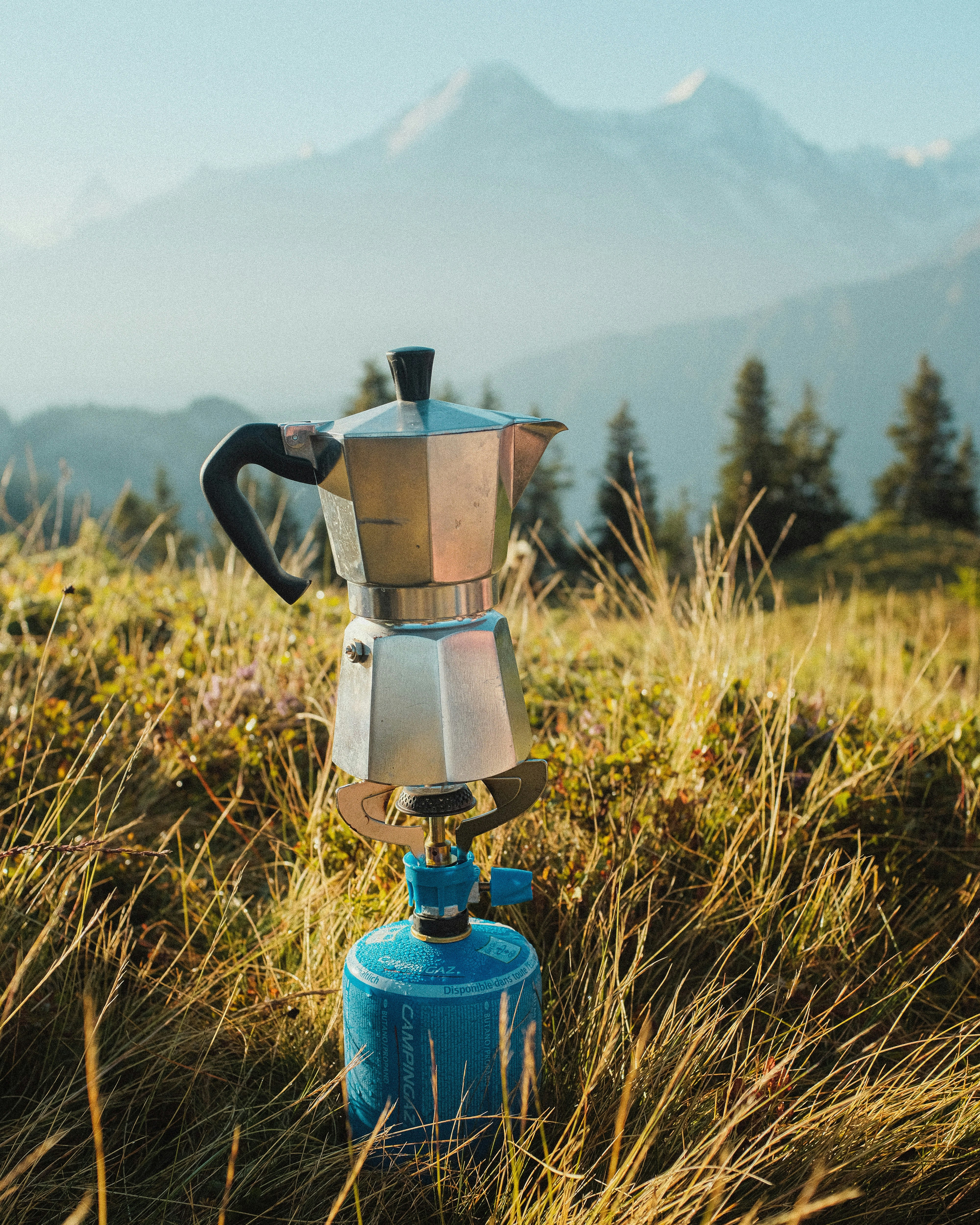 blue and silver coffee pot on green grass field during daytime